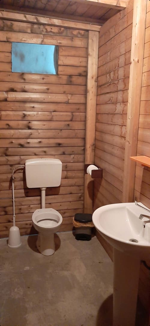 Bagno in legno al Baia Dorica Camping Village con toilette, lavabo e piccola finestra blu