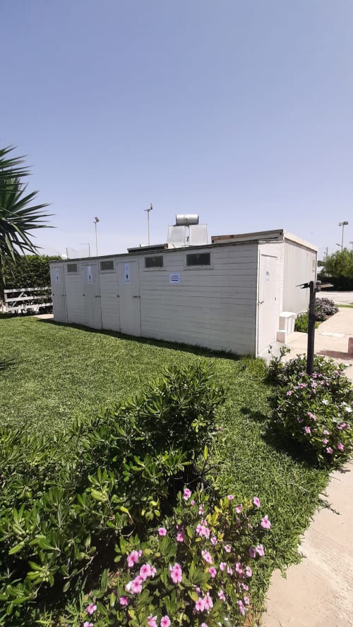 Piazzole con bungalow al Baia Dorica Camping Village di Vittoria, prato curato e fiori rosa