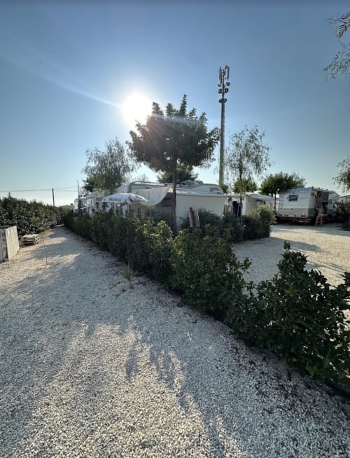 Baia Dorica Camping Village a Vittoria con caravan parcheggiati, sentieri in ghiaia, siepi verdi e torre di comunicazione