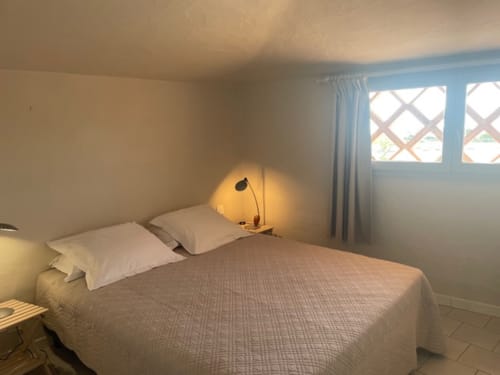 Chambre lumineuse à la Résidence Cala Di Sole avec lit queen-size, oreillers blancs, lampadaire arqué et fenêtres vue mer à Lecci