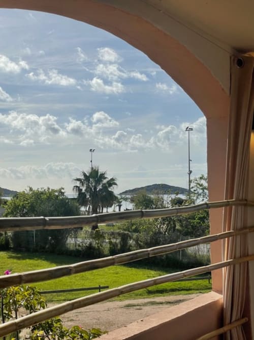 Vue mer depuis la terrasse de l'appartement Résidence Cala Di Sole à Leccia en Corse avec palmiers et collines