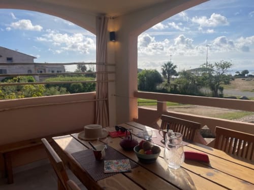Terrasse avec vue sur mer à la Résidence Cala Di Sole, Lecci, avec table de salle à manger donnant sur le paysage côtier