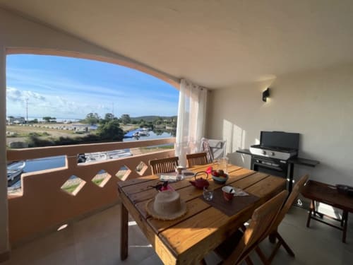 Balcon lumineux avec vue sur la marina et la campagne à la Résidence Cala Di Sole, Lecci, table de repas et vue sur la mer