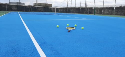 Campo da tennis blu al Camping Village Baia Dorica a Vittoria con palline e attrezzature disposte sul terreno
