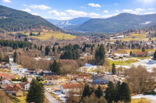 Vue aérienne de la vallée du Tholy avec le Chalet le Grizzli niché parmi les pentes boisées et prairies verdoyantes des Vosges