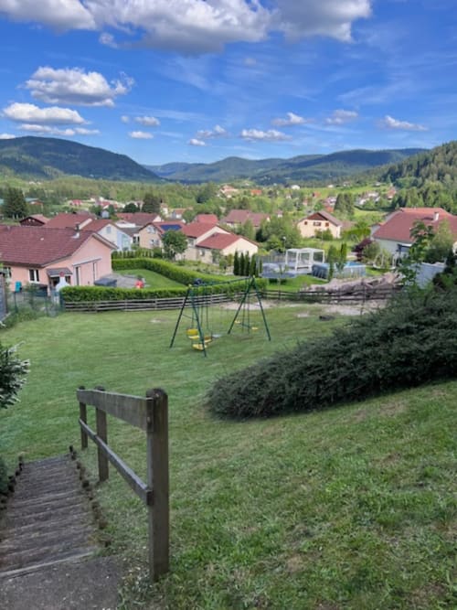 Vue panoramique de la vallée de Le Tholy avec chalets résidentiels, pelouses verdoyantes, balançoire et montagnes des Vosges