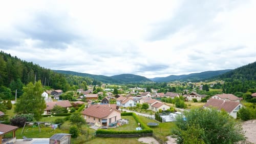 Vue aérienne du Chalet le Grizzli au Tholy avec les montagnes des Vosges et la vallée boisée