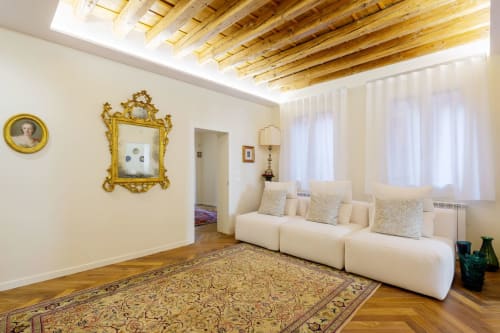 Elegant Venice villa living room with cream modular sofa, ornate gold mirrors, exposed wooden beams, and traditional Italian