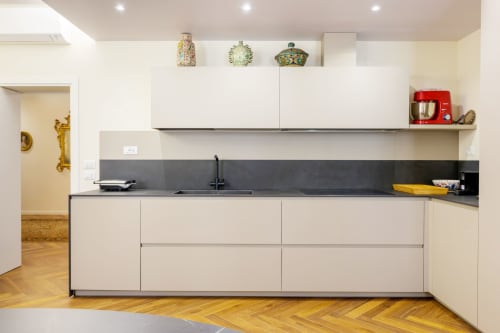 Modern white kitchen with dark countertop, black sink, and decorative pendants in Bealux villa, Venice