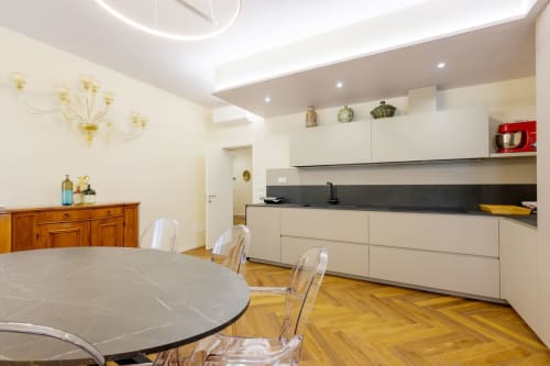 Modern kitchen and dining area in San Vio villa, Venice with white cabinetry, marble table, and wooden flooring