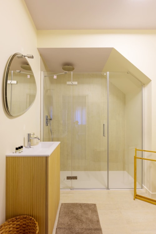 Modern bathroom in Venice villa with yellow vanity, glass shower enclosure, round mirror, and heated towel rack