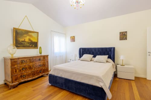 Elegant bedroom at Bealux villa in Venice with navy upholstered bed, wooden dresser, and cream bedding