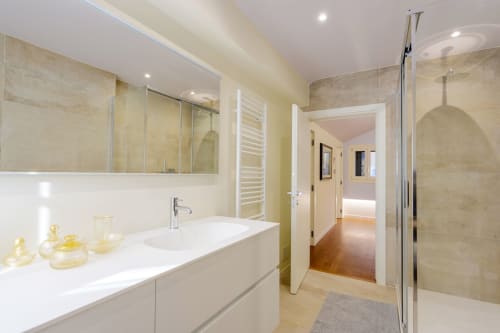 Modern bathroom in San Vio villa, Venice with white vanity, large mirror, glass shower, and heated towel rack