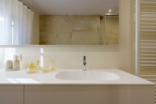 Modern bathroom vanity with white countertop, oval sink, and large mirror at Bealux villa in Venice