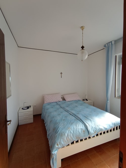 Camera luminosa a Tales of Abruzzo ad Atessa con biancheria blu, comodini bianchi e lampada a sospensione