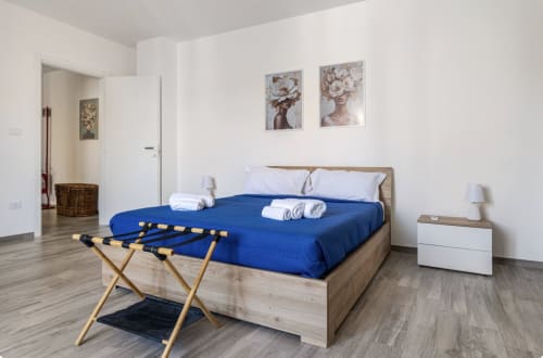Camera da letto moderna nell'appartamento di Brindisi con letto blu, struttura in legno, comodino bianco e arredamenti contemporanei