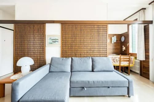 Modern gray sectional sofa in Venetian apartment with wooden partition screens and dining area