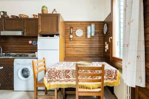 Cozy Venice apartment kitchen-dining area with wooden cabins, dining table, washing machine, and period furnishings at Bealux
