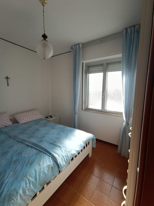 Camera luminosa con biancheria azzurra decorata, vista mare dalla finestra e pavimenti in cotto