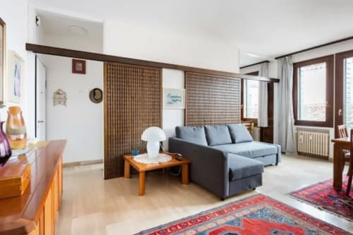 Spacious Venice apartment living room with blue sofa, wooden furniture, and landmark views at Bealux hotel