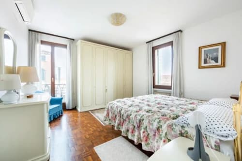 Bright bedroom at Bealux apartment in Venice's Zattere with floral bedding, cream wardrobes, and landmark views