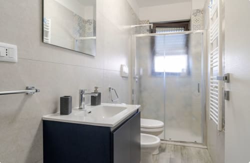 Bagno moderno nell'appartamento di Brindisi con piastrelle bianche, vanity scura e ampio box doccia