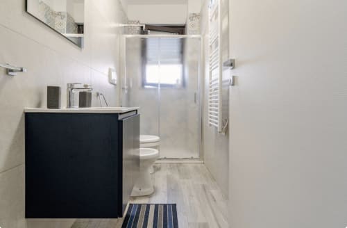 Bagno moderno nell'appartamento Brindisi Comfort House con vanity scuro, piastrelle bianche, cabina doccia e scaldasalviette