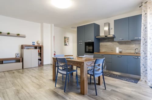 Cucina moderna e zona living nella Brindisi Comfort House con cabinetry blu, tavolo in legno e vista sulla città