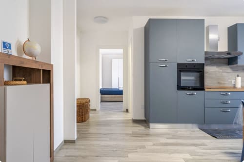 Moderna zona cucina-soggiorno open-plan nell'appartamento Brindisi Comfort House con arredamento grigio, pavimento in legno e camera da letto
