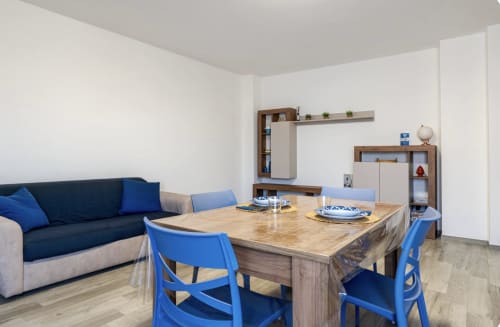 Soggiorno moderno a Brindisi con sedie blu, tavolo da pranzo in legno, divano blu navy e arredi contemporanei