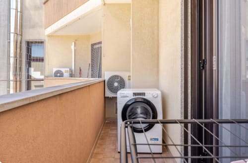 Zona lavanderia dell'appartamento a Brindisi con lavatrice bianca, climatizzatore e soleggiata balconata presso Epico Locazioni Turistiche