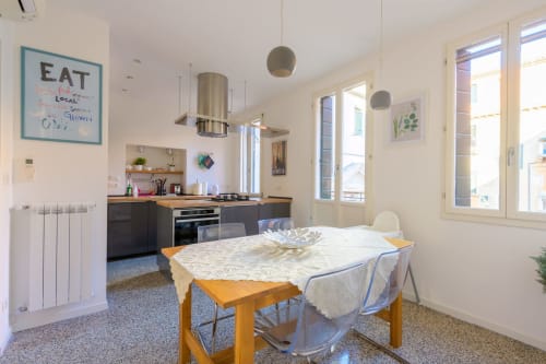 Cuisine-séjour luminaire et contemporaine à Venezia avec table en bois, mobilier sombre, suspensions et vue sur la ville