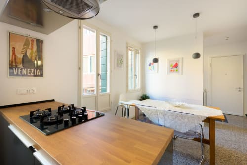 Cuisine lumineuse d'appartement vénitien avec cuisinière à gaz, table en bois et vue sur la ville