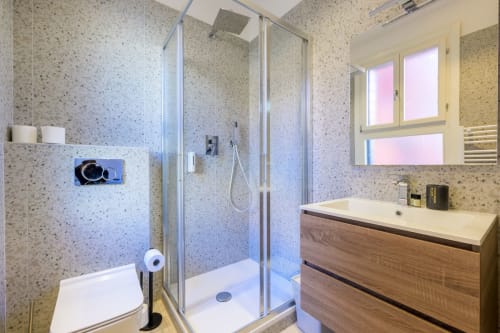 Salle de bain moderne de l'appartement Bealux à Venise avec carrelage moucheté, douche vitrée, meuble vasque en bois et miroir