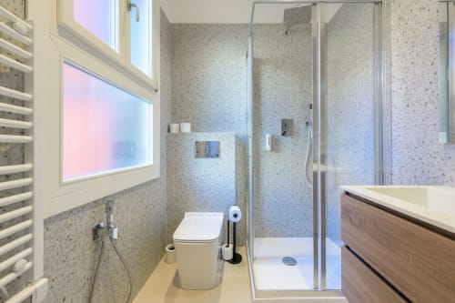 Salle de bain moderne avec carrelage en terrazzo, douche à l'italienne, toilettes et meuble vasque en bois à l'appartement Bealux à Venise
