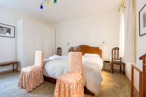 Spacieuse chambre d'appartement vénitien avec lit en bois, mobilier élégant et vue sur la ville