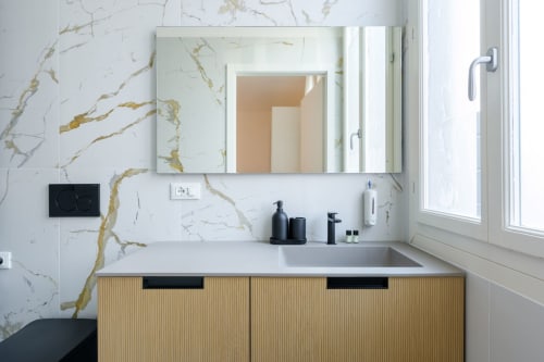 Salle de bain moderne dans un appartement vénitien avec murs en marbre, meuble-lavabo en bois, miroir et vue sur la ville