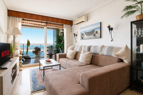 Espacioso salón de la Marina Suite en Riurau Home, Calpe, con balcón con vistas al mar, sofá seccional beige y diseño moderno