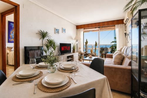 Comedor de Marina Suite en Riurau Home, Calpe, con vistas al mar, mesa elegantemente decorada y Netflix en TV