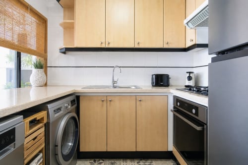 Cocina moderna en Marina Suite de Riurau Home, Calpe con muebles de madera, electrodomésticos de acero inoxidable y salpicadero de azulejos blancos
