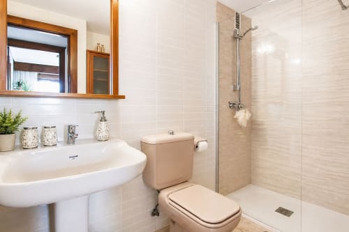 Baño moderno en Marina Suite de Riurau Home, Calpe con ducha walk-in, lavabo pedestal y espejo de madera