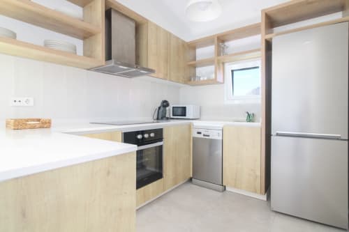 Modern kitchen in Xanadú apartment at Riurau Home, Calpe, with wooden cabinets, stainless steel appliances, and white