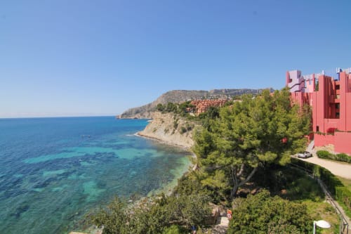 Xanadú apartment at Riurau Home in Calpe with red building, Mediterranean Sea, rocky coastline and pine trees