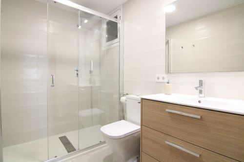 Modern bathroom in Xanadú apartment at Riurau Home, Calpe with glass shower enclosure, wooden vanity and white fixtures