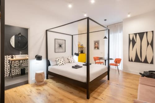 Deluxe double suite at Suite Maradona Naples featuring black canopy bed, modern artwork, orange chairs, and ensuite bathroom