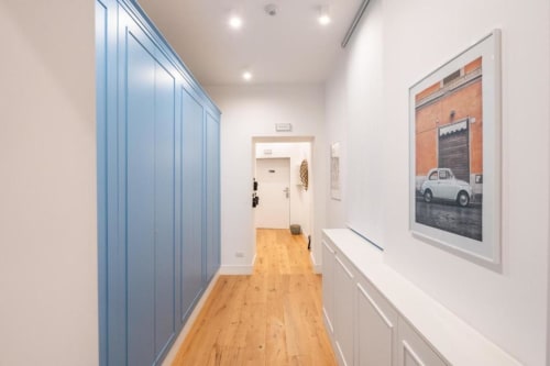 Modern hallway in Suite Maradona Naples BnB with blue wardrobe, white walls, framed car artwork, and wooden flooring