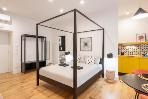 Modern Deluxe Double Room at Suite Maradona Naples featuring black four-poster bed, yellow cabinet, and contemporary decor
