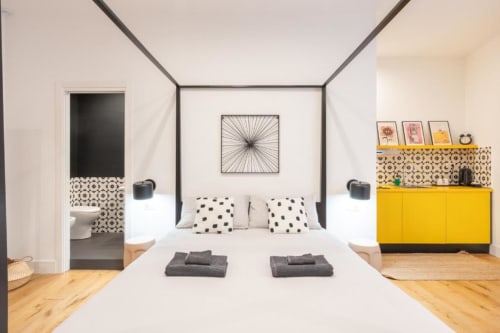 Modern Deluxe Double Room at Suite Maradona Naples with canopy bed, yellow cabinet, patterned tiles, and wooden floors