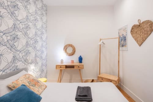 Bright modern bedroom at Suite Maradona Naples with wooden furniture, blue patterned wallpaper, and woven decorative accents