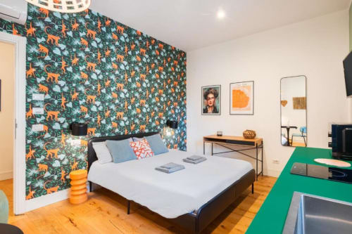 Superior double room at Suite Maradona Naples with jungle wallpaper, white bedding, kitchenette, and green kitchen counter.